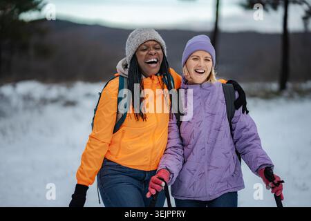 Happy diverse women friends hiking in winter snow Stock Photo