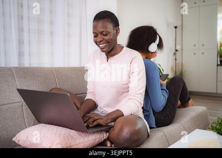 Mother working from home while daughter listens to music Stock Photo