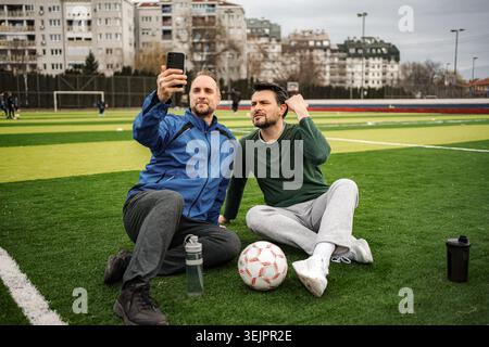 Friends taking selfie on soccer field during break Stock Photo