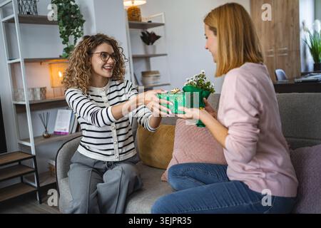 Two friends Sitting on a Couch, One Holding a Present Stock Photo