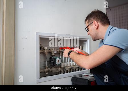 Plumber working on heating pipes inside building wall Stock Photo