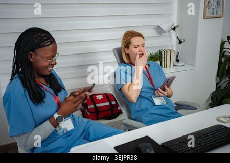 Overworked healthcare workers taking a break with smartphones Stock Photo