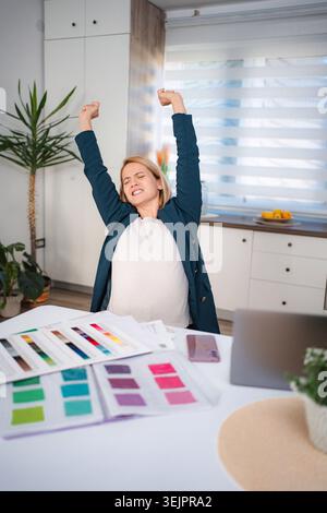 Pregnant woman stretching while working from home Stock Photo