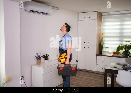 Technician looking and checking air conditioning unit with toolbox Stock Photo