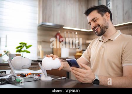 Man installing home security camera, connecting it to smartphone app Stock Photo