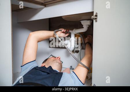 Plumber working on kitchen sink drain pipe system Stock Photo