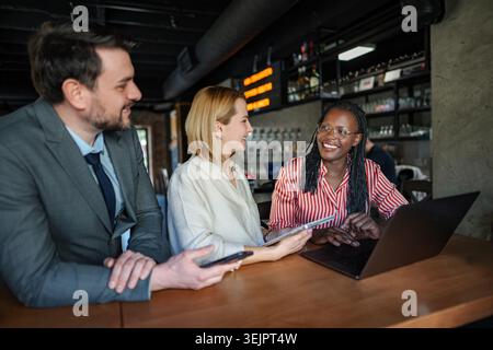 Diverse business colleagues working on laptop and tablet during informal meeting Stock Photo
