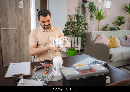 Technician installing surveillance camera at home following instructions on laptop Stock Photo
