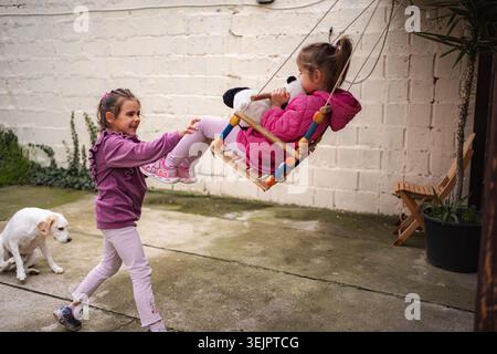 Happy sisters playing together with stuffed animal in home backyard Stock Photo