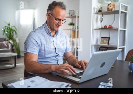 Middle aged Caucasian man working on laptop at home Stock Photo