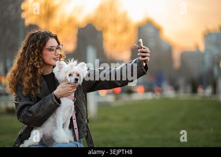 Woman and dog taking a selfie outdoors during sunset Stock Photo