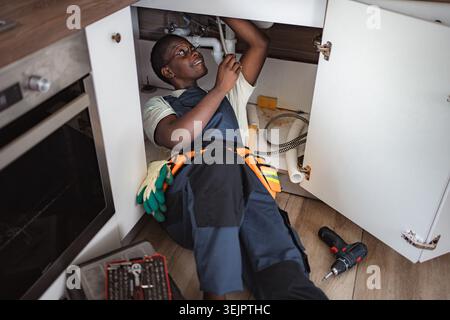 Plumber fixing pipes under kitchen sink Stock Photo
