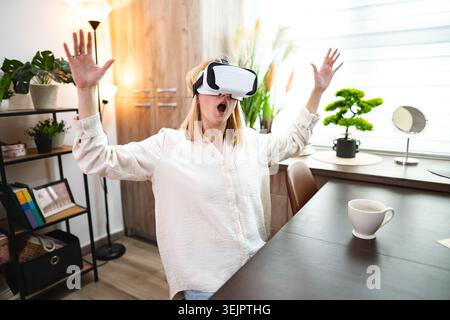A person immersed in virtual reality sits at a desk, expressing pure joy. Stock Photo