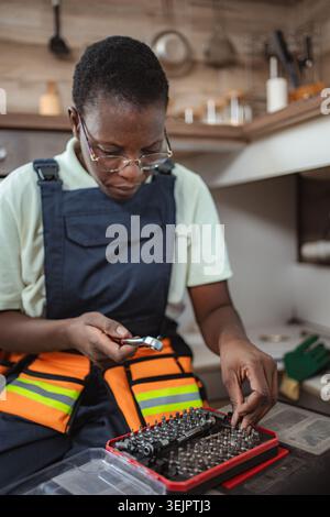 Female technician choosing right tool for fixing kitchen sink Stock Photo
