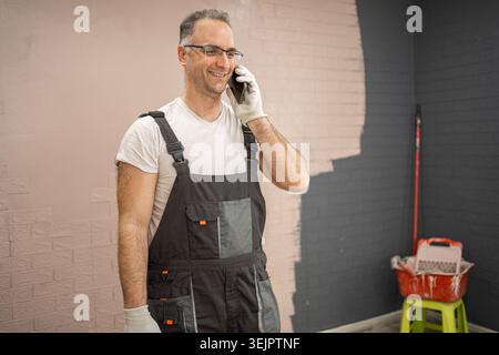 Man in Overalls Talking on Cell Phone Stock Photo