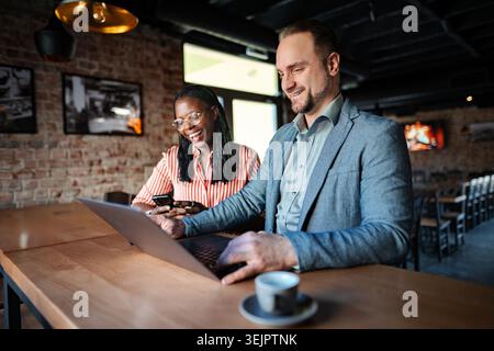Business colleagues collaborating on laptop in coffee shop Stock Photo