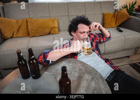 Young man drinking beer at home after party Stock Photo