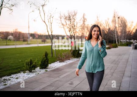Young businesswoman walking and talking on smartphone in a park Stock Photo