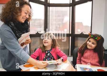 Female teacher helping elementary students at language school class Stock Photo
