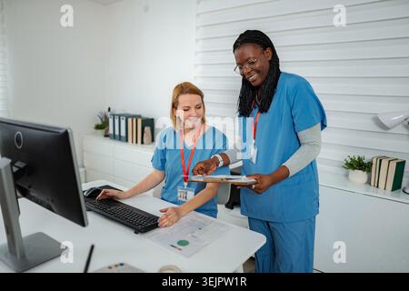 Female nurses collaborating on computer during busy shift Stock Photo