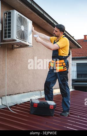 Technician checking air conditioner with thermal imaging camera on a roof Stock Photo