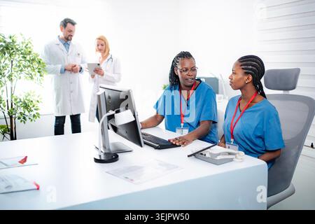 Healthcare team working on a computer and tablet in a modern clinic Stock Photo