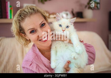 Woman smiling and holding white Ragdoll cat Stock Photo