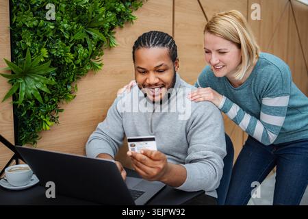 Happy interracial couple online shopping using credit card Stock Photo