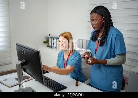 Diverse nurses collaborating on computer in modern medical office Stock Photo