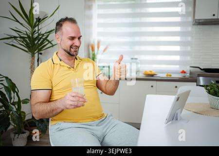Man giving thumbs up during video call at home Stock Photo