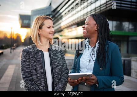 Diverse businesswomen colleagues discussing work using digital tablet Stock Photo