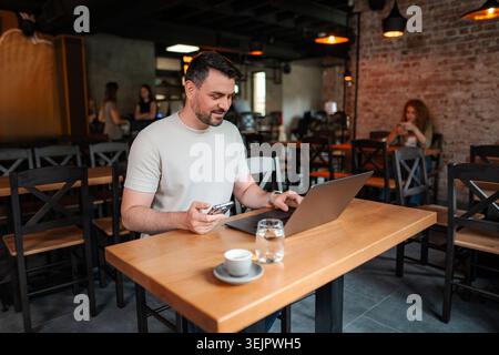 Freelancer working on laptop and using smartphone in cafe Stock Photo