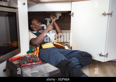 Plumber fixing pipes under kitchen sink Stock Photo