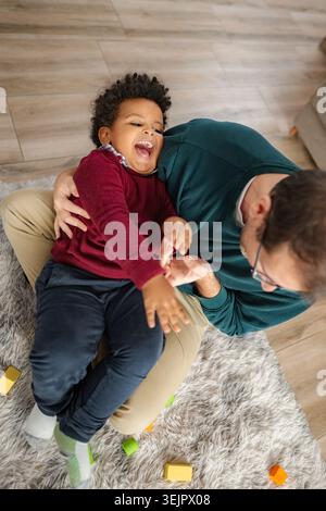 Father and son playing at home, dad tickling laughing child Stock Photo