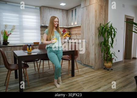 Joyful morning in a cozy kitchen with fresh juice and vibrant plants Stock Photo