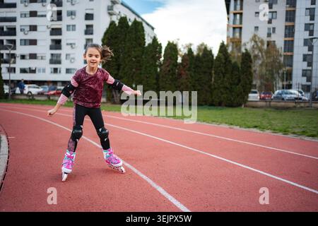 Girl rollerblading on running track wearing protective gear Stock Photo