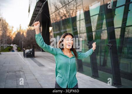 Businesswoman celebrating success outside office building Stock Photo
