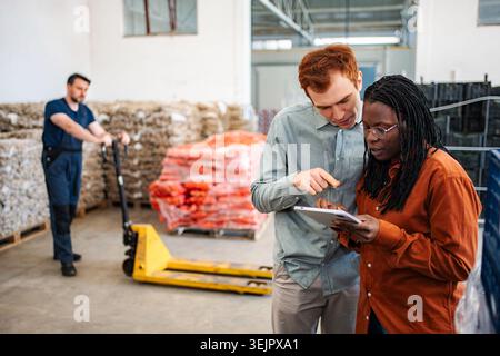 Diverse warehouse colleagues using digital tablet for inventory management Stock Photo