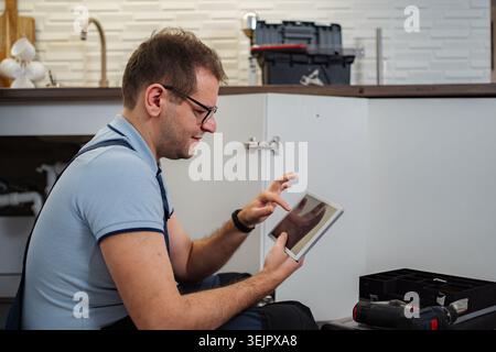 Plumber using tablet for kitchen sink repair Stock Photo