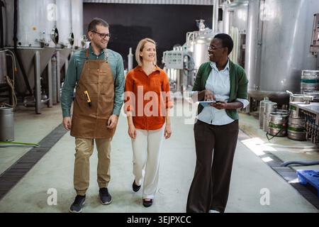 Colleagues walking through brewery discussing production process Stock Photo