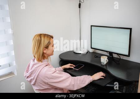 Young woman working from home using computer and mouse Stock Photo
