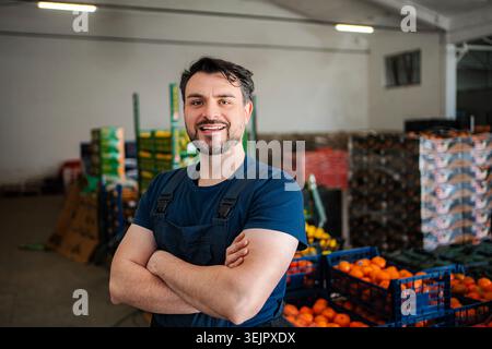 Man with arms crossed smiling in fruit warehouse Stock Photo