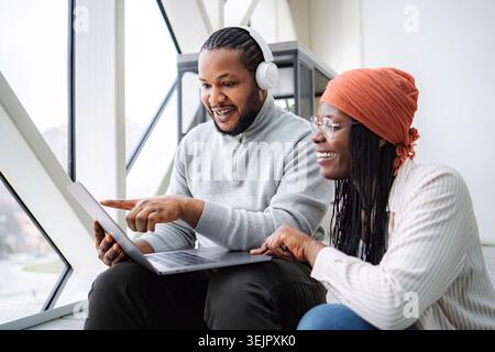 Two diverse colleagues smiling and working together on a laptop Stock Photo