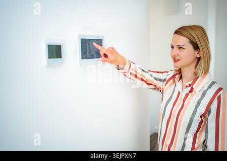 Woman using smart home control panel adjusting climate indoors Stock Photo