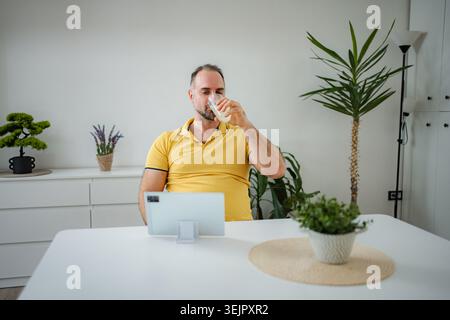 Man drinking juice while using tablet at home Stock Photo