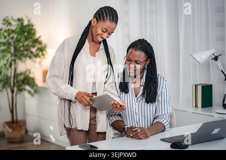 Black women collaborating using tablet in office Stock Photo