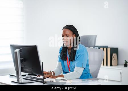 African American nurse typing on computer in office Stock Photo
