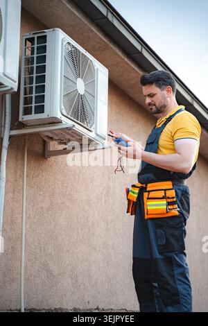 Electrician is checking an air conditioner with a multimeter Stock Photo