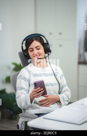 Pregnant woman confidently connecting remotely using smartphone and headset Stock Photo