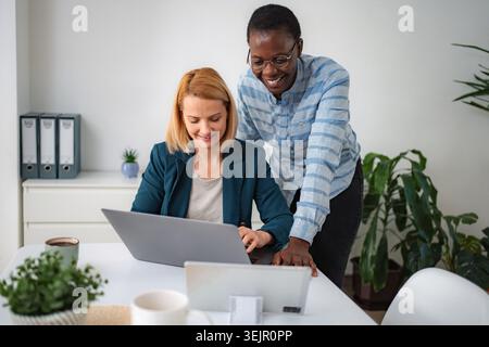 Diverse businesswomen collaborating efficiently on laptop in modern office Stock Photo